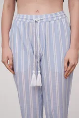 Pantalón babucha celeste con rayas verticales blancas, cintura elástica con cordón y detalle de borlas.