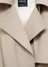 Trench coat de corte oversize en color beige, con cuello de solapa, cierre frontal, cinturón ajustable a la cintura, trabillas en hombros y puños con detalle de botón.