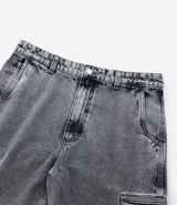 Pantalón de jean modelo baggy con bolsillos cargo laterales, cintura con trabillas y cierre frontal con botón y cremallera.
