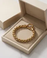 Pulsera de eslabones trenzados en acero con baño de oro, con cierre circular frontal tipo mosquetón.