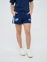 Bermuda deportiva azul marino Umbro del Club Nacional de Football, con bolsillos laterales, cordón ajustable en la cintura y detalles con líneas laterales. Incluye el escudo del club y el logo de la marca bordados.
