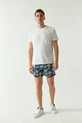 Short de baño con estampado botánico en tonos azules, amarillos y blancos. Presenta cintura elástica con cordón ajustable, bolsillos laterales y un bolsillo trasero. Confeccionado en tejido ligero de secado rápido con efecto lavado.