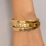 Brazalete rígido dorado con tres piedras ovaladas de cuarzo rosado.
