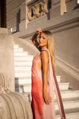 Vestido largo de satén con estampado degradado en tonos rosado, naranja y fucsia. Presenta escote en V, tirantes finos y un pañuelo integrado al cuello.