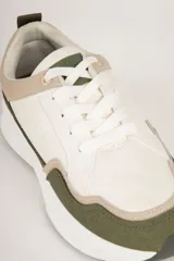 Zapatillas deportivas de gamuza color beige, con recortes en negro y marrón claro. Suela blanca de goma con base marrón.