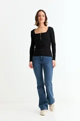 Remera de manga larga, color blanco, con tejido acanalado y escote cuadrado. Presenta un cierre metálico dorado en el centro del escote.