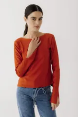 Remera de manga larga con cuello bote, confeccionada en tejido de algodón. Presenta un corte recto y aberturas laterales en los puños.