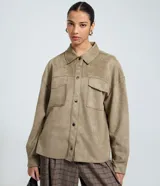 Camisa de corte regular confeccionada en gamuza sintética color beige, con cuello inglés, cierre frontal abotonado, mangas largas con puños ajustados y bolsillo tipo cargo en el pecho.