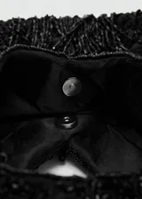 Bolso de mano negro cubierto de abalorios y flecos con asa integrada y estructura triangular.