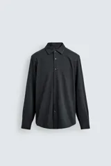 Camisa de corte relajado confeccionada en tejido de algodón con textura. Presenta cuello italiano, cierre frontal con botones y mangas largas con puños abotonados.