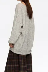 Jersey de punto largo con corte oversize, escote en pico pronunciado y mangas largas con volumen. Incluye un top interior de tirantes en satén con detalles de encaje en el escote.