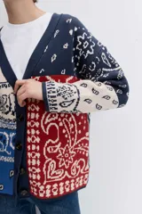 Cardigan de punto con diseño jacquard estilo patchwork en tonos azul, rojo y crema. Presenta un estampado tipo bandana, cuello en V, cierre frontal con botones y mangas largas.