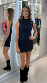 Vestido corto ajustado de cuello alto y sin mangas, confeccionado en tela con acabado brillante y efecto drapeado en los laterales.