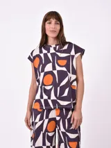 Remera de manga corta con cuello redondo, corte recto y estampado geométrico abstracto en tonos blanco, morado oscuro y naranja.