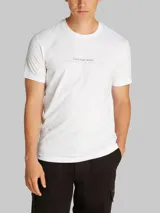 Remera blanca de algodón con cuello redondo y mangas cortas. Presenta un estampado en relieve de Calvin Klein Jeans en el pecho.