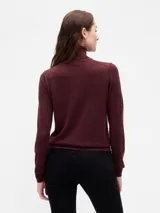 Buzo de punto con cuello alto tipo polera, de corte ajustado y manga larga.