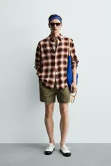 Camisa de corte regular fit confeccionada en tejido fluido de algodón y viscosa. Presenta un diseño de cuadros, cuello solapa, manga larga con puños abotonados, bolsillo en el pecho y cierre frontal con botones.