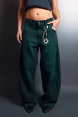 Jean de corte holgado y tiro medio, color verde oscuro, con costuras frontales verticales y diseño de paneles laterales. Cuenta con cierre de botón y bragueta, y presillas para cinturón.