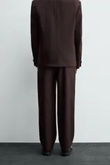Pantalón de traje straight fit color marrón oscuro, confeccionado en tejido con lana. Cuenta con bolsillos frontales, bolsillos traseros de vivo y cierre frontal con cremallera y gancho metálico oculto.