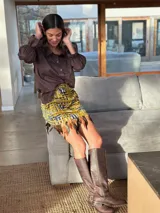 Minifalda con estampado geométrico en tonos amarillo, negro y gris, con detalle de plumas en el ruedo.