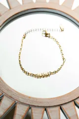 Pulsera dorada de acero quirúrgico con baño de oro 18k y cadena de eslabones ovalados. Dije con la palabra “mamá”.