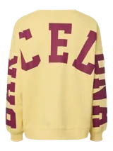 Buzo oversize de color amarillo con cuello redondo y mangas largas, con estampado de letras en color bordó en las mangas.