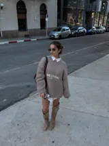 Bota estilo texana de caña media, confeccionada en gamuza color beige. Presenta un diseño slouchy con arrugas naturales, punta fina y taco cuadrado de madera. Incluye costuras decorativas en la puntera y detalles en cuero liso en la parte superior de la caña.