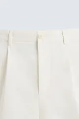 Bermuda de corte regular fit, color blanco hueso, confeccionada en tejido de algodón y lino. Presenta pliegues frontales, bolsillos delanteros y bolsillos traseros de plastrón.