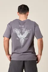 Remera marrón de corte holgado con estampado de un ave y texto en la espalda.