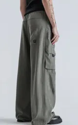 Pantalón cargo de silueta oversize, color gris oscuro/verde militar, con cintura elástica y cinturón de cinta negra ajustable con hebilla de plástico. Presenta bolsillos cargo amplios a los lados de las piernas.