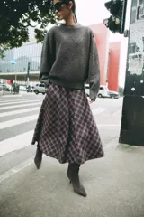 Falda midi de tiro alto ZARA Woman Collection, con diseño evasé y estampado de cuadros en tonos oscuros con líneas rojas y blancas. Cuenta con cierre lateral con cremallera oculta.