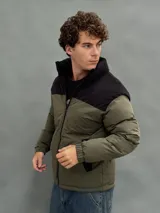 Campera puffer con capucha, diseño bicolor en verde oliva y negro, cierre frontal y bolsillos laterales.
