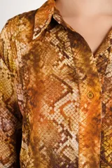Camisa de viscosa con estampado animal print tipo piel de serpiente en tonos marrones y rojizos, de corte corto, manga larga y cuello clásico.