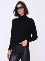 Sweater negro de cuello alto, mangas largas con botones decorativos en los puños y corte ajustado.