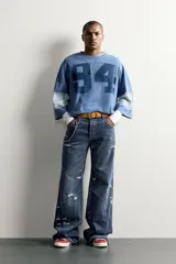 Jeans flare fit de denim azul oscuro con roturas y costuras decorativas en las perneras. Tiro medio y diseño de cinco bolsillos.