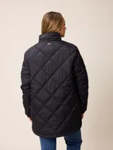Campera larga acolchada con diseño de rombos, cierre frontal completo y cuello alto. Presenta puños elásticos y un pequeño logo aplicado en el pecho.