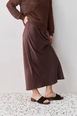 Falda midi color negro al bies, confeccionada en tela de textura suave y caída fluida, de diseño minimalista y silueta recta.