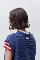 Chaleco tejido azul de calce relajado, silueta recta, cuello redondo, hombros caídos y diseño de punto con textura calada.