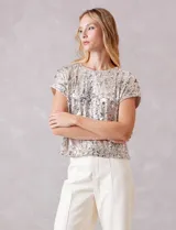 Blusa de manga corta cubierta de lentejuelas en tono champagne, con cuello redondo a la base y forro interno a tono.