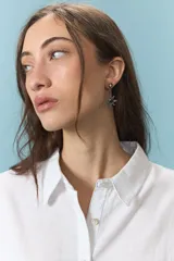 Caravanas colgantes con diseño de estrella de ocho puntas en metal plateado envejecido, con incrustación de piedra azul en el centro y pequeño detalle de cristal en la parte superior.