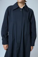 Trench midi color negro, confeccionado en mezcla de algodón y nylon con acabado repelente al agua. Presenta diseño con tajos laterales, bolsillos internos y etiqueta de marca en la espalda.