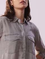 Camisa celeste de tencel con cuello con solapa, abertura central con botones ocultos, bolsillos delanteros y mangas largas regulables con presilla y botón.