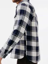 Camisa de manga larga con estampado de cuadros en tonos azul marino y blanco. Presenta cuello clásico, cierre frontal con botones y dos bolsillos con solapa en el pecho.