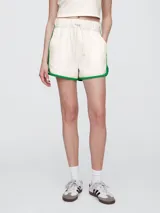 Short de piqué color crema con ribetes en color verde, cintura elástica con cordón de ajuste y diseño deportivo.