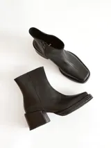 Bota corta de cuero negro con punta cuadrada y taco bloque texturizado. Presenta cierre lateral y costura central en el empeine.