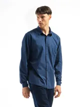 Camisa de manga larga azul, confeccionada en algodón, con corte clásico y bolsillo en el lado izquierdo del pecho.