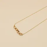 Collar de cadena fina en oro 9k con un detalle central de eslabones entrelazados.