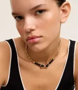 Collar corto dorado con eslabones dobles, cierre de gancho y colgantes grandes revestidos en poliuretano negro.