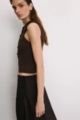 Falda pantalón de tiro alto en color marrón oscuro, con diseño de superposición que combina un pantalón recto con una falda envolvente con lazadas laterales. Cuenta con cierre lateral oculto.