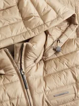 Campera color beige de nailon reciclado, con cuello alto, capucha con cordón ajustable, cierre de cremallera frontal, bolsillos laterales con cremallera, cinturón con hebilla metálica y logo de Calvin Klein en el pecho.